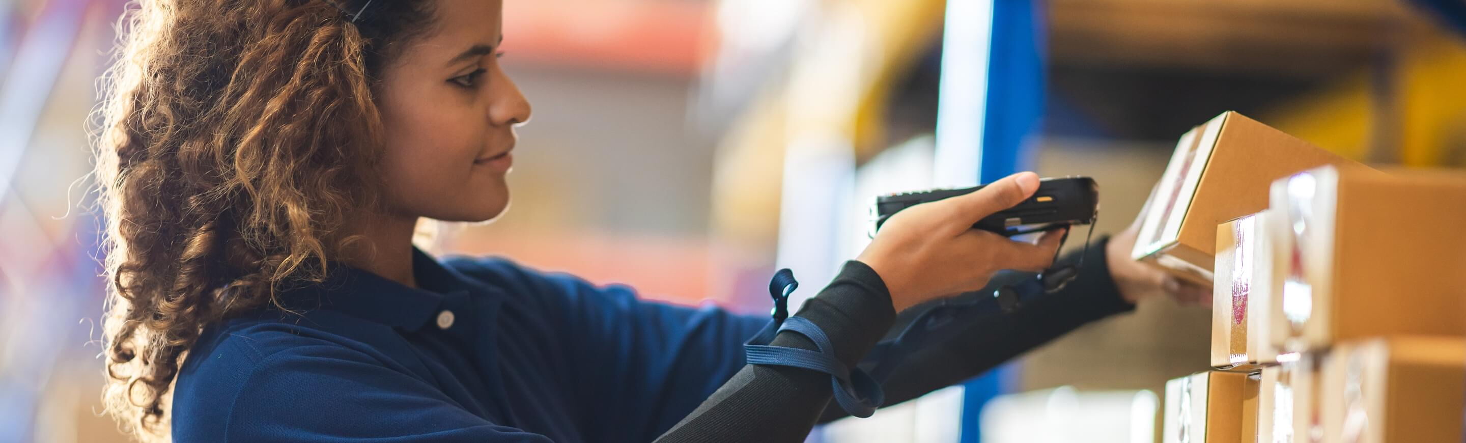 Eine Frau scannt sorgfältig ein Paket in einem Lager, während sie in der Lagerlogistik arbeitet.